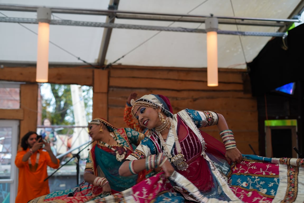 Two dancers in traditional Rajasthani jewellery and saris mid-pose during a Garba performance