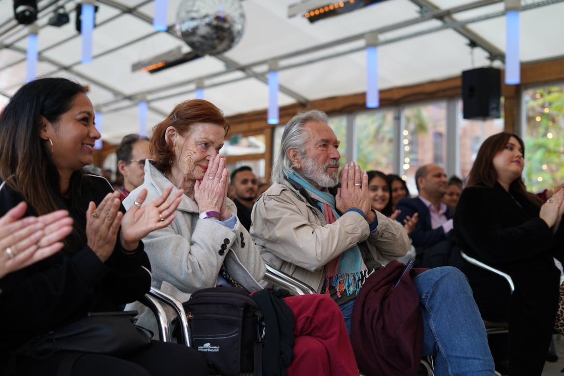 Close-up of an audience of different ages and backgrounds clapping during a Diwali performance