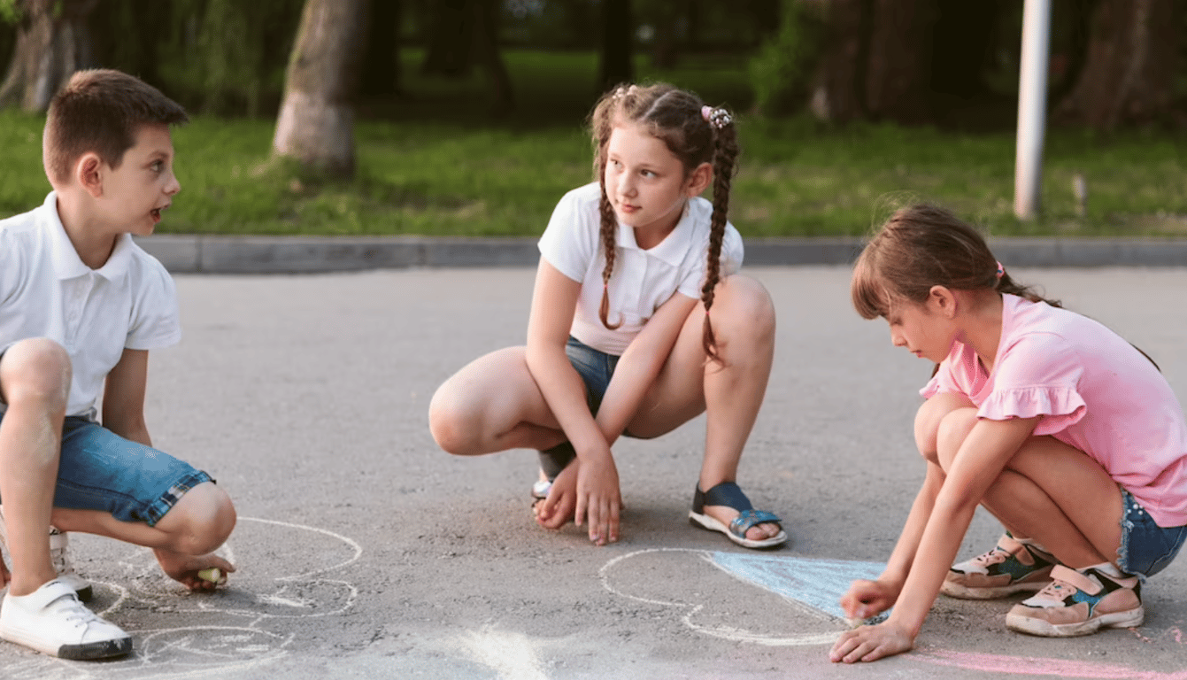 Маленькие дети во время рисования на асфальте