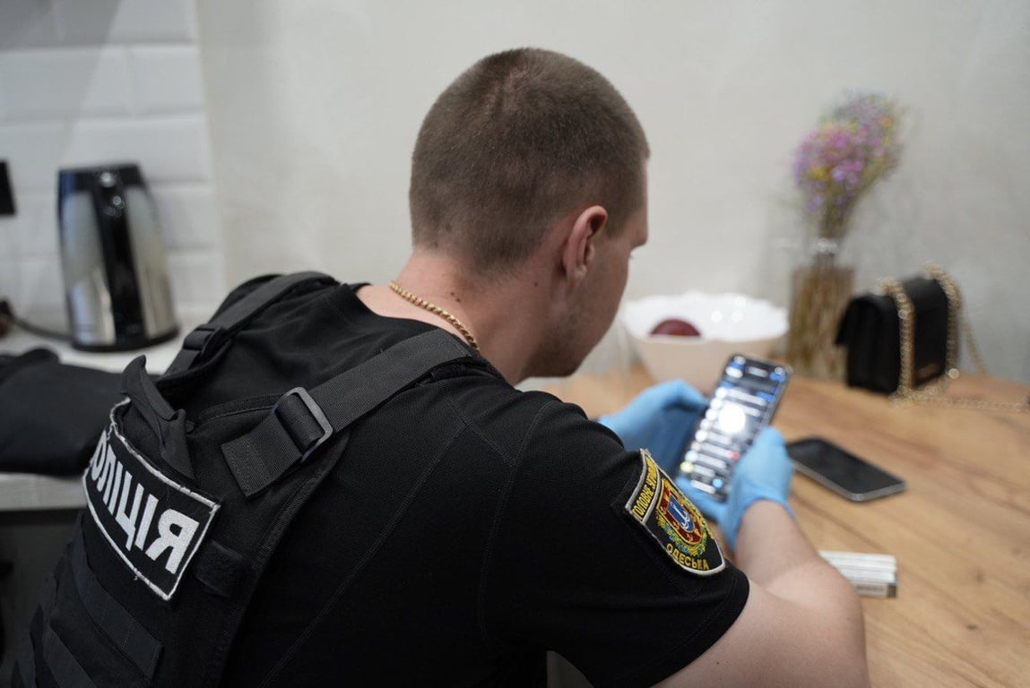 Правоохоронець обстежує телефон зловмисниці. Фото: ГУНП в Одеській області