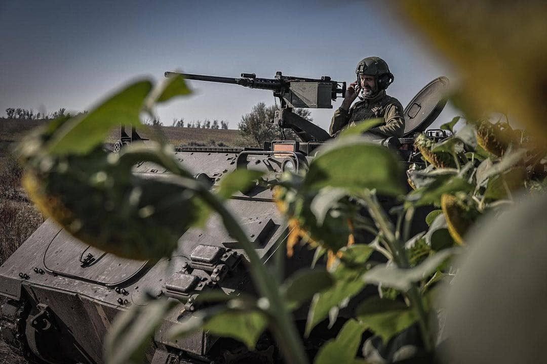 Українські бійці на військовій техніці серед соняшника