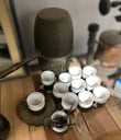Antiguedades: Juego de Te de Porcelana acompañadas de cucharitas de metal y un singular artefacto para agua caliente