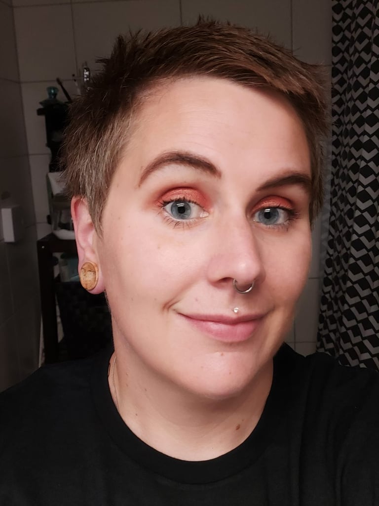 A photo of a straight edge woman with a septum piercing looking into the camera