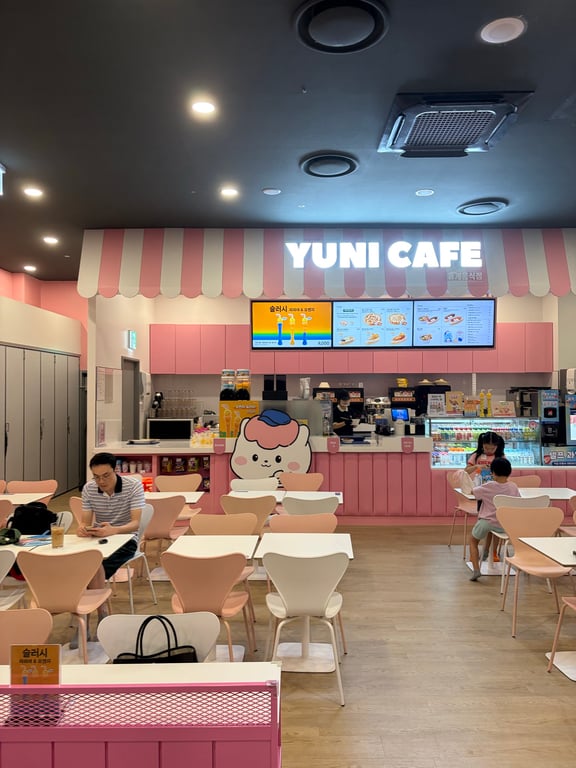 챔피언더블랙벨트 YUNI CAFE 내부 — 핑크 줄무늬 인테리어의 카페 카운터와 키즈 의자