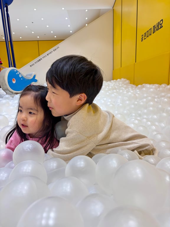 월드킹 구로점 대형 볼풀장에서 오빠가 동생을 꼭 안고 있는 따뜻한 남매 사진
