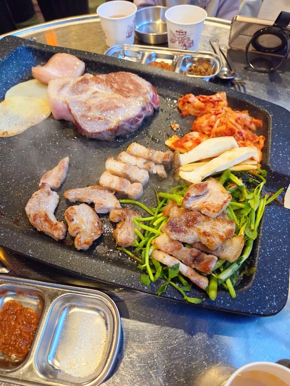 김숙성 불판 위 고기와 미나리 함께 굽는 장면