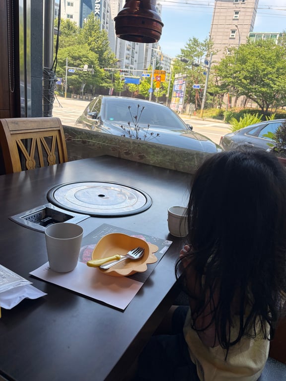 훈장골 하남점 창가석에 앉은 아이와 아이용 식기 세팅 모습