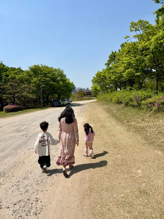 엄마와 8세 남아, 5세 여아 남매가 손을 잡고 미사경정공원 산책로를 걷는 뒷모습