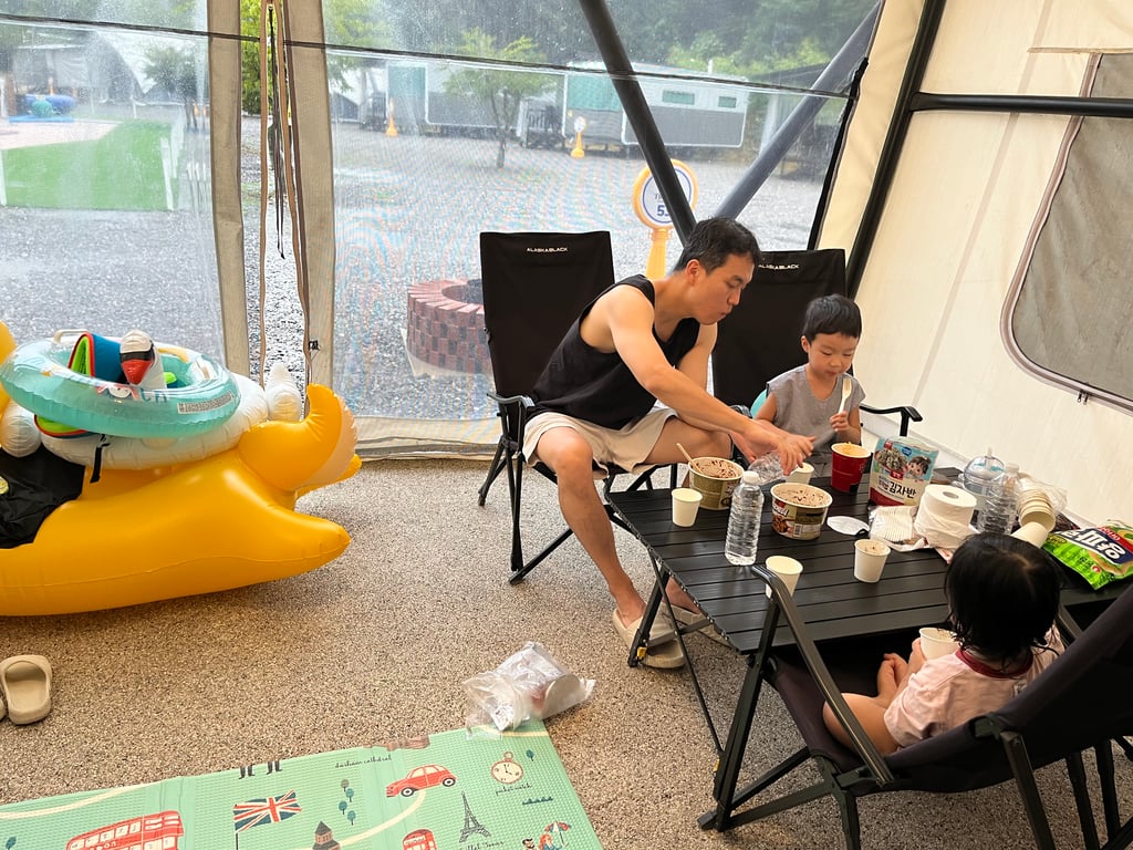 비 오는 날 더세븐글램핑카라반 돔 텐트 안에서 가족이 식사하는 모습