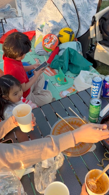 구리한강시민공원에서 캠핑테이블에 둘러앉아 편의점 라면을 먹는 가족