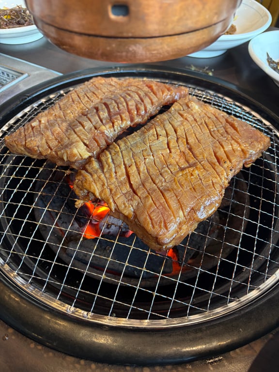 훈장골 하남점 숯불에 양념 돼지갈비 굽는 장면 불꽃 위 두 덩어리