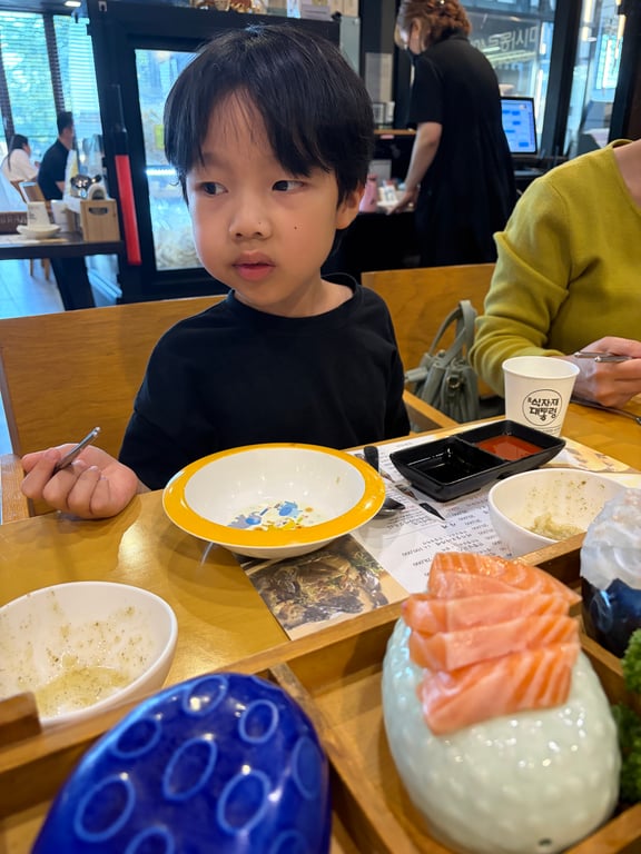 하남 어시장에서 식사 중인 남자아이 — 연어회 앞에서 즐겁게 먹는 모습