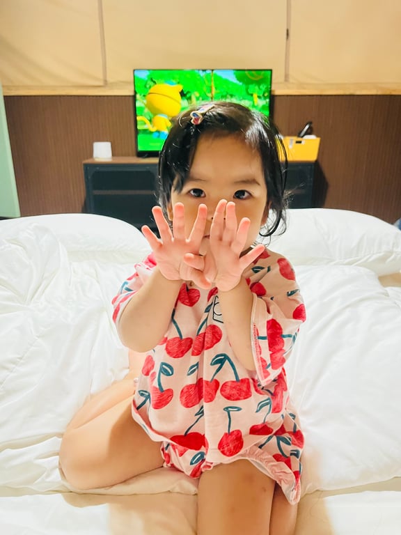 글램핑 텐트 안에서 TV 보며 포즈 취하는 4세 딸 — 벽걸이 TV와 깨끗한 침구