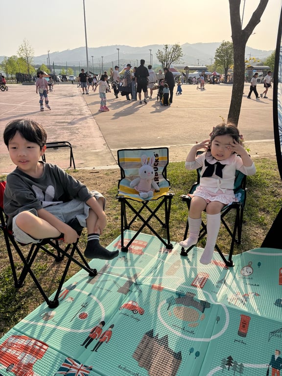 구리한강시민공원 잔디밭에서 캠핑의자에 앉아 쉬는 남매