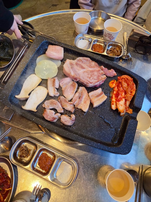 김숙성 불판 위에 숙성 목살과 마늘 김치 굽는 장면