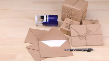 Post envelopes and parcels, stamps and stationery in one go on a natural wood table. Post or delivery concept