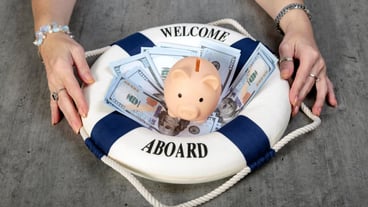 Piggy bank on Stacked dollars banknotes and lifebuoy with text Welcome on Board on wooden desk background Woman hands with life buoy Assets wealth money saving and security by insurance concept
