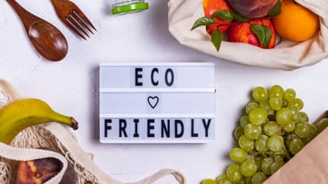 Eco friendly wrote on a board near fruits in eco bags
