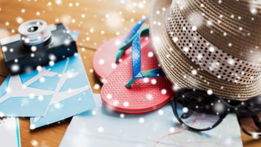 Concept for tourism, winter vacation and objects - close-up of travel card, flip-flops, hat and camera with flight tickets on wooden table at home