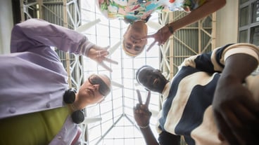 Low angle portrait of multiethnic group of young people looking down at camera in circle standing in urban setting