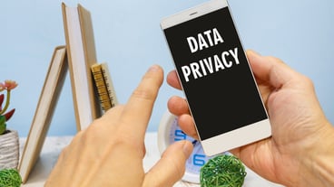 Smartphone in hand with the inscription Data privacy next to office supplies