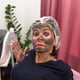 Woman with face smeared with carbon mask in beauty salon