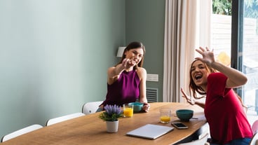 Joyful women having lunch and outstretching arms towards camera