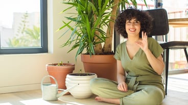 Young pretty arab woman at home, with a watering can and plants