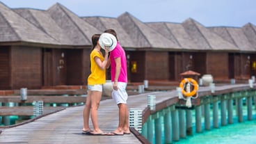 Young couple on beach jetty near water villa in honeymoon