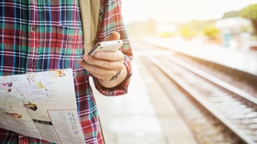 Young tourist with a beard holding a map and using Mobile phone travel concept