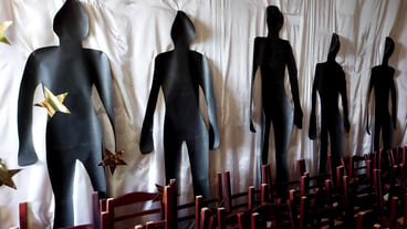 Black silhouettes of people made of cardboard on a white fabric background