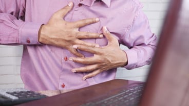Young man suffering pain in heart and holding chest with hand