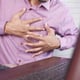 Young man suffering pain in heart and holding chest with hand