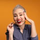 Portrait of smiling woman with make-up brush in mouth against orange background