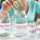 Young woman putting money in glass jar with her money savings. Concept of financial investment, economy growth and bank savings.