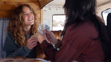 Two female lovers playing cards during winter trip