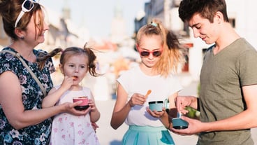 Mother and children having ice cream in city during sunny day
