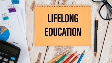 Notebook with the text Lifelong Education on the office table among the stationery.