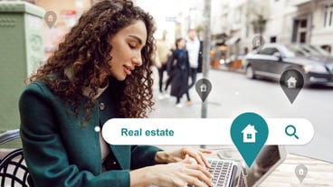Woman searches for real estate options on laptop in urban setting while enjoying a coffee at a