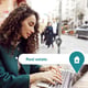 Woman searches for real estate options on laptop in urban setting while enjoying a coffee at a