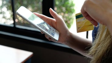 Cropped image of a woman holding a credit card and using a phone