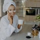 smiling woman with hydrogel spots under her eyes enjoying a hot tea while talking on the phone