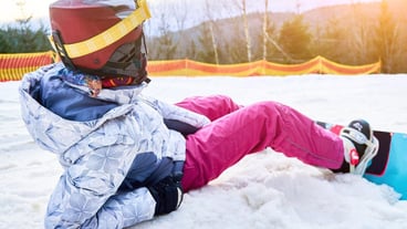 Girl with snowboard in snowy mountains
