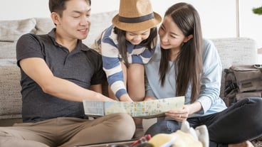 A parent and daughter are at home in their living room with a map.