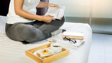 Women's book or newspaper reading and coffee breakfast in bed during the morning.