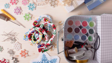 Beads, a box of colored beads, and jewelry-making tools. Preparation for handcrafting