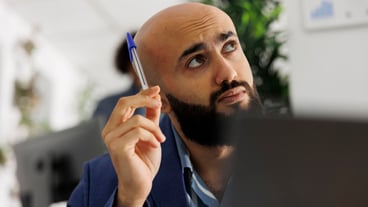Arab entrepreneur thinking and looking away while analyzing sales strategy on laptop. Young company employee managing financial data while working in start up business office