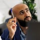Arab entrepreneur thinking and looking away while analyzing sales strategy on laptop. Young company employee managing financial data while working in start up business office