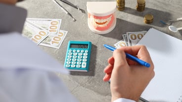 Man with pen in hand notepad cash calculator jaw and dental instruments on gray background
