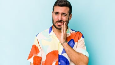 Young caucasian man isolated on blue background having a strong teeth pain molar ache